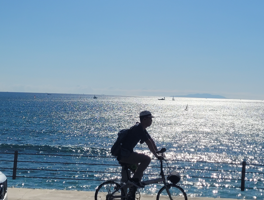 Man cycling by Kamakura beach, Kanagawa.